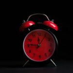 a red and black alarm clock on a black background